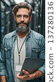 Confident bearded man data center information technology network server system administrator grey hair eyeglasses laptop lanyard casual shirt 137280136