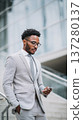 Confident businessman smartphone outdoor, African American male professional, modern office background, urban city, grey suit 137280137