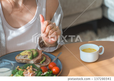 一位時尚的年輕亞裔女性正在客廳餐桌旁用餐。 137280341