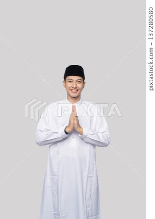 Respectful greeting gesture. Peaceful Asian Muslim man displaying respectful afro greeting gesture Respectful greeting gesture. Peaceful Asian Muslim man displaying respectful afro greeting gesture 137280580