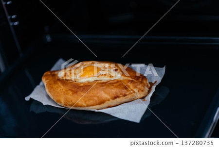 Khachapuri on baking paper is baked in the oven. We cook khachapuri with our own hands at home. Delicious quick dishes Khachapuri.  137280735