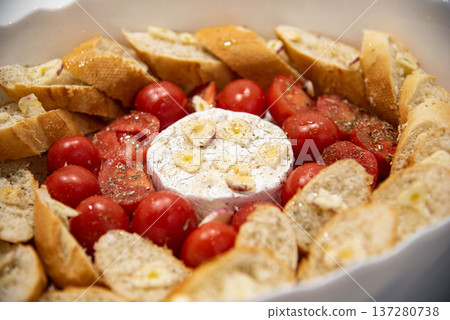 Camembert cheese baked with tomatoes and baguette, herbs and garlic. An excellent appetizer for wine. View from above. Camembert cheese baked with tomatoes and baguette, herbs and garlic. An excellent appetizer for wine. View from above. 137280738