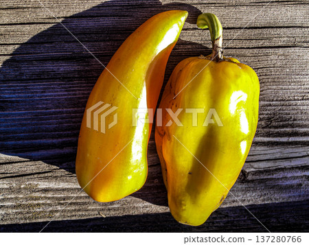 Two yellow ripe sweet peppers on an old wooden board Two yellow ripe sweet peppers on an old wooden board 137280766