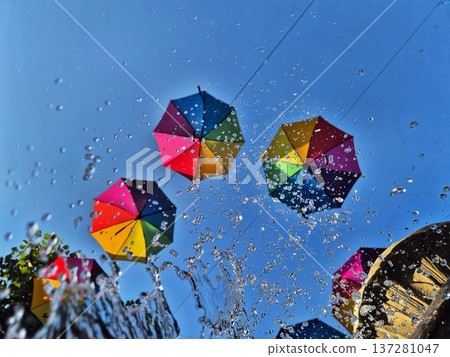 Multicolored umbrellas against the sky and splashes of water. Multicolored umbrellas against the sky and splashes of water. 137281047