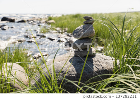Balanced stones atop a rock beside gentle waves 137282211