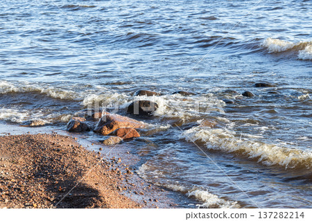 Small waves gently lap against a rocky shore Small waves gently lap against a rocky shore 137282214