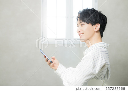 看他的智能手機的一個年輕人 看他的智能手機的一個年輕人 137282666