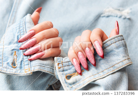 Woman showing trendy pink stiletto nails with denim jacket Woman showing trendy pink stiletto nails with denim jacket 137283396