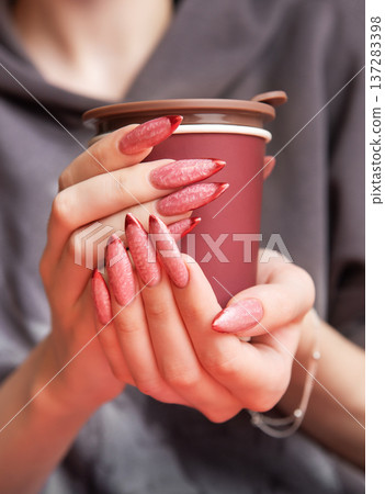 Woman holding insulated cup with long red ombre manicure 137283398