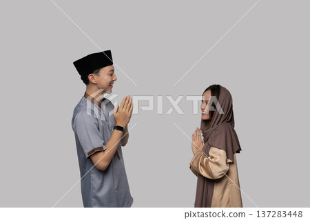 Calm individuals performing mirrored prayer in modest attire Calm individuals performing mirrored prayer in modest attire 137283448
