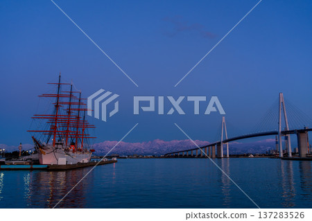 The pink Abenrot peaks of the Tateyama mountain range with Shinminato Bridge and Kaiwomaru in the foreground from Kaiwomaru Park in the evening 137283526