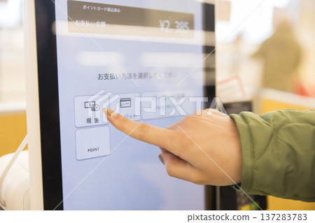 Woman's hand paying at a self-checkout Woman's hand paying at a self-checkout 137283783