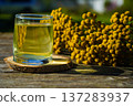 On a wooden tray rests a cup of golden tansy tea a herbal remedy with pronounced choleretic and spasm-soothing effects. 137283937