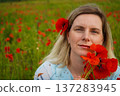 Woman poppies field. Happy woman is resting in the rays of the sun sitting in the poppy field. 137283945