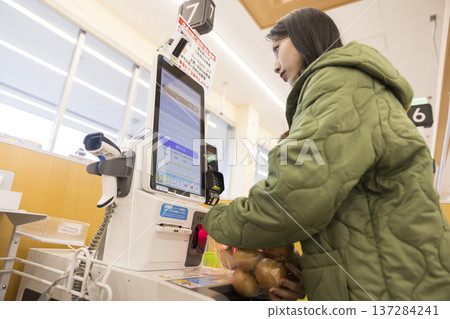 A young woman paying at a supermarket self-checkout 137284241