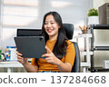Asian woman freelancer office worker looking watching on tablet sitting on leather chair at company. 137284668