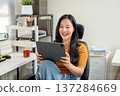 Asian woman freelancer or office worker watching video on tablet sitting on leather chair at company 137284669