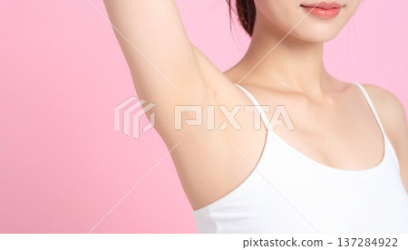 一位年輕女子在粉紅色背景下展示她除毛後的腋下特寫。這是一張身體護理和美容圖片。 137284922
