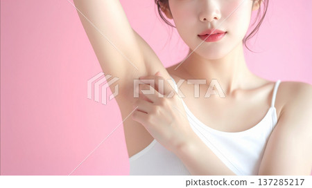 Close-up of a young woman showing her armpits after hair removal against a pink background. Body care and beauty image. 137285217