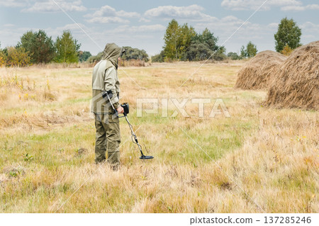 Man with electronic metal detector device working on outdoors. Man with electronic metal detector device working on outdoors. 137285246