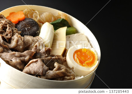 盛滿食材的壽喜燒便當盒,在黑色背景下拍攝。 盛滿食材的壽喜燒便當盒,在黑色背景下拍攝。 137285443