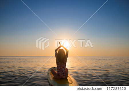 Young woman walking on sup board by the sea during summer vacation Young woman walking on sup board by the sea during summer vacation 137285620