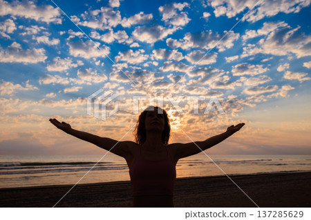 Happy woman enjoying sunrise at the beach during summer vacation 137285629