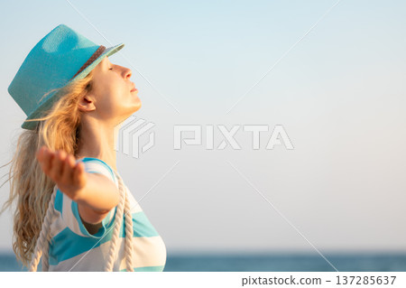 Young happy woman enjoying by sunrise against blue sea and sky on summer vacation Young happy woman enjoying by sunrise against blue sea and sky on summer vacation 137285637