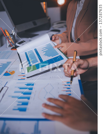 Two business people talk project strategy at office meeting room. Businessman discuss project planning with colleague at modern workplace while having conversation and advice on financial data report. 137287635