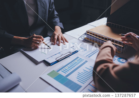 Two business people talk project strategy at office meeting room. Businessman discuss project planning with colleague at modern workplace while having conversation and advice on financial data report. 137287657