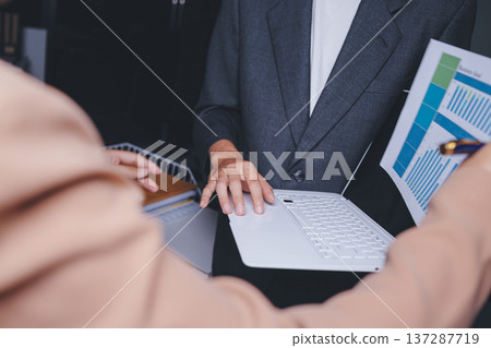 Two business people talk project strategy at office meeting room. Businessman discuss project planning with colleague at modern workplace while having conversation and advice on financial data report. Two business people talk project strategy at office meeting room. Businessman discuss project planning with colleague at modern workplace while having conversation and advice on financial data report. 137287719