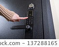 A woman opens a modern smart door lock with a digital keypad using a code. 137288165