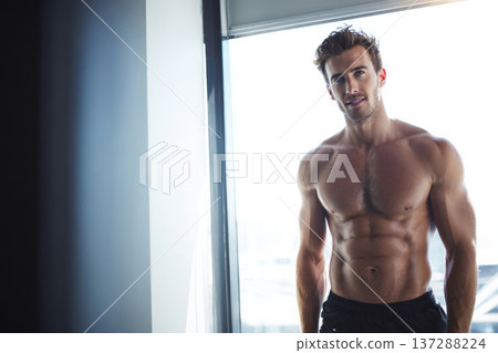 fit male front facing with toned abs in modern office gym corner, clean bright lighting. 137288224
