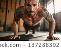 athletic tattooed male performing burpees in modern gym studio, intense action, bright natural 137288392