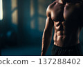 faceless muscular male front view with sculpted abs, modern industrial gym softly blurred, dramatic 137288402