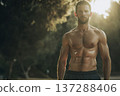 athletic male front facing with toned abs after outdoor run, light sweat, park environment softly 137288406