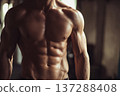 faceless muscular man facing camera showing defined abs, strong torso, neutral pose, minimal gym 137288408