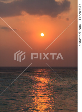 Golden sun dips low over calm ocean waters Golden sun dips low over calm ocean waters 137289813