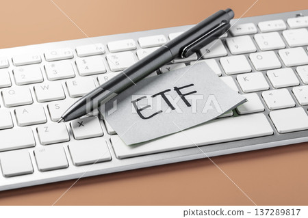 ETF investment concept with ETF text on sticky note on computer keyboard and pen on brown background ETF investment concept with ETF text on sticky note on computer keyboard and pen on brown background 137289817