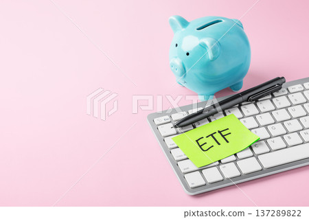 ETF concept, blue piggy bank and computer keyboard with ETF green sticky note on pink background, financial planning and saving 137289822