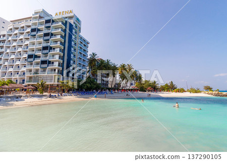 Sunlit beach meets turquoise waters and a towering resort 137290105