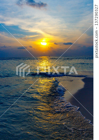 Golden sun sets over calm ocean waves Golden sun sets over calm ocean waves 137290327