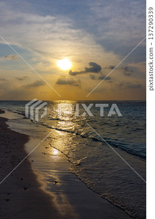 Golden sun sets over calm ocean waves Golden sun sets over calm ocean waves 137290339