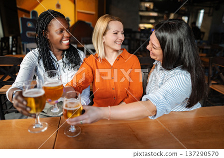 Diverse women friends toasting beers at brewery bar Diverse women friends toasting beers at brewery bar 137290570