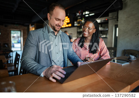 Business colleagues collaborating on laptop in restaurant bar Business colleagues collaborating on laptop in restaurant bar 137290582