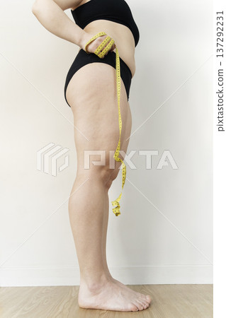 Woman measuring body with tape for weight loss Woman measuring body with tape for weight loss 137292231
