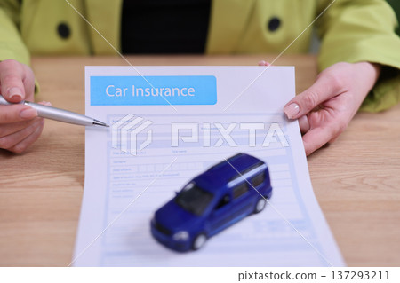 Signing car insurance with a model vehicle on paperwork during a bright afternoon consultation Signing car insurance with a model vehicle on paperwork during a bright afternoon consultation 137293211