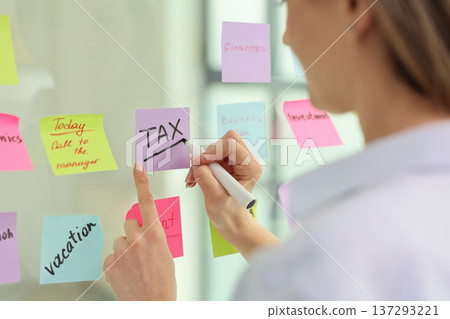 Creative planning session focuses on tax deadlines with colorful sticky notes in a modern office setting 137293221