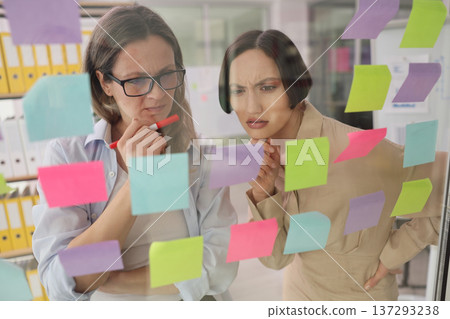 Team brainstorming session unfolds in a vibrant office setting with colorful sticky notes and engaged expressions Team brainstorming session unfolds in a vibrant office setting with colorful sticky notes and engaged expressions 137293238