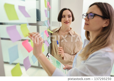 Creative brainstorming session brings ideas to life with colorful sticky notes in modern office setting Creative brainstorming session brings ideas to life with colorful sticky notes in modern office setting 137293250
